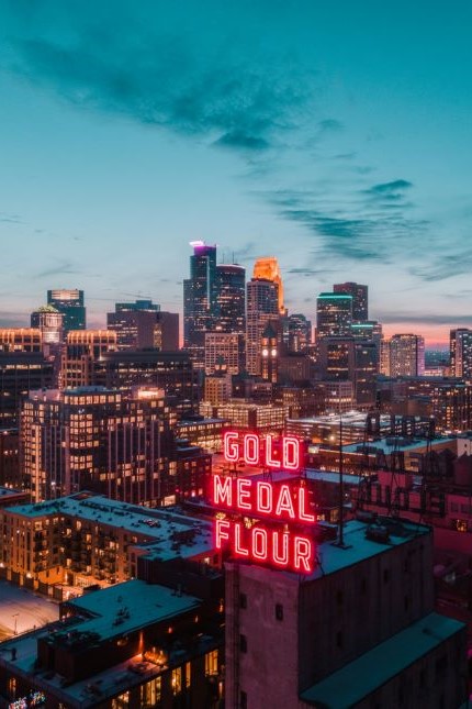 Buildings in Minneapolis in the evening with the neon Gold Medal Flour sign lit up.